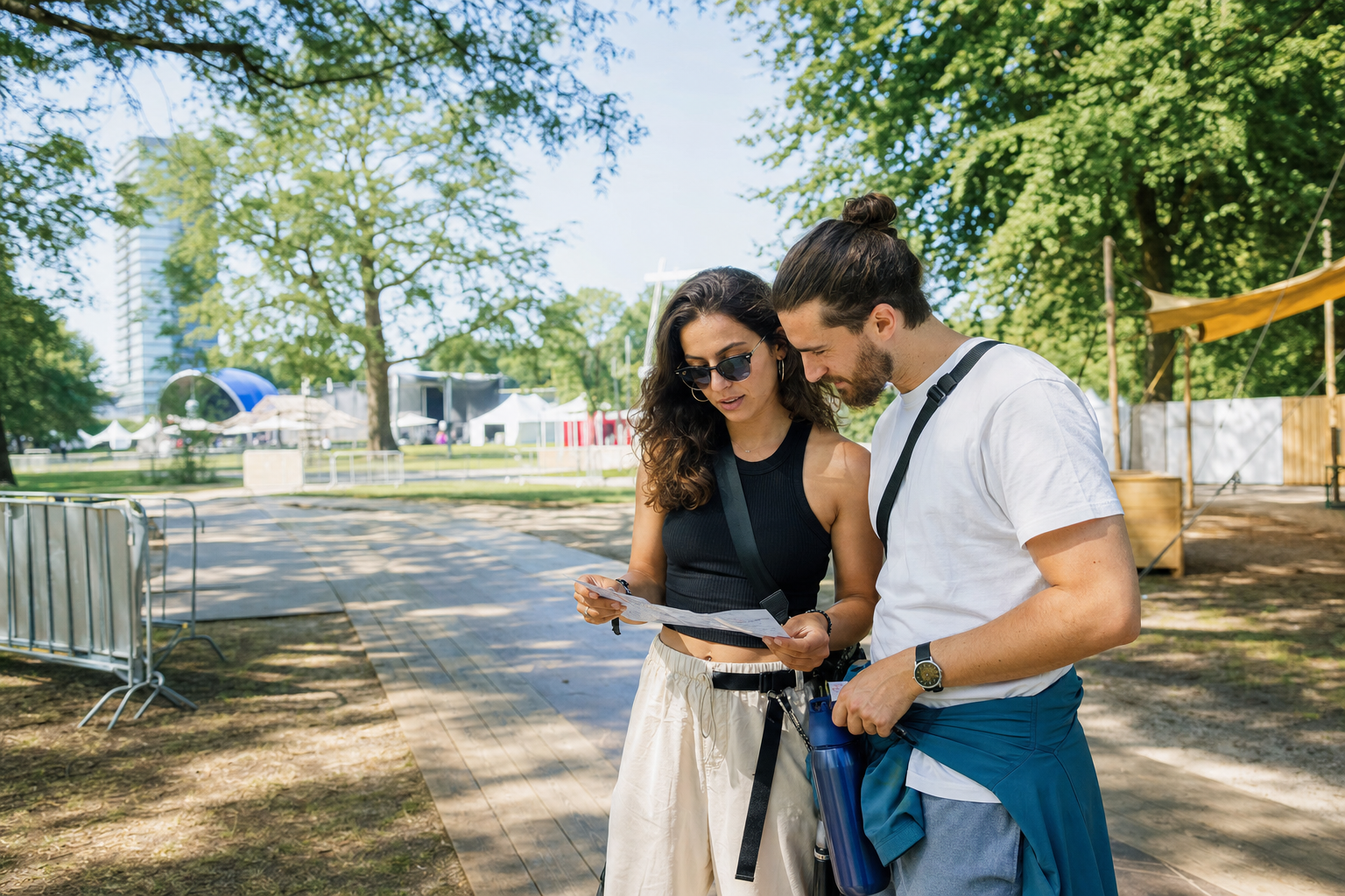 Twee bezoekers bekijken samen een programma in een groen stadspark voor een festival